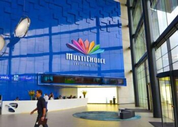 Multichoice and DSTV logo displayed in a modern office interior with people in the background.