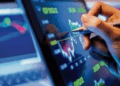 Hand analyzing stock market chart on table